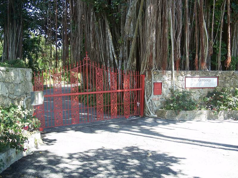 The red entrance gate of The Kampong under banyan trees